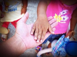  child's hand on adult hand