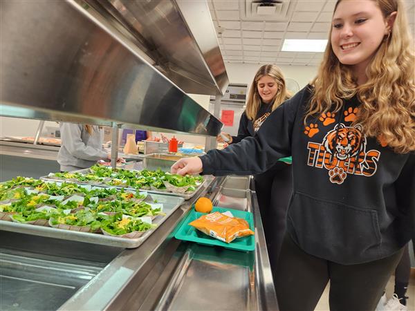 Student taking salad from lunch options