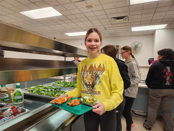 Student with salad on lunch tray