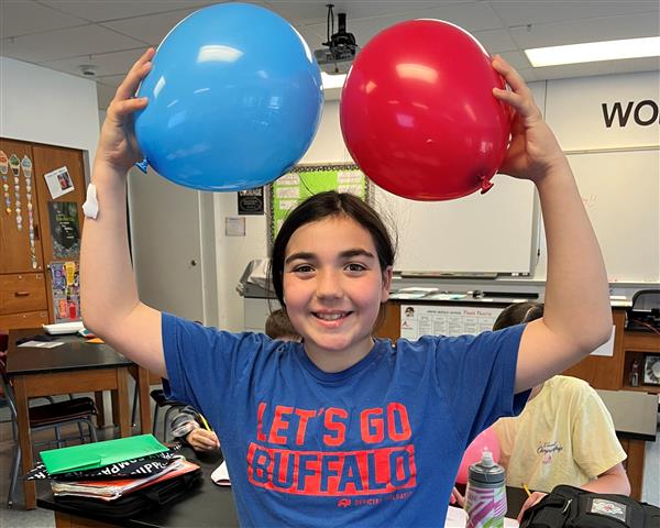 Student showing static electricity with hair and balloons