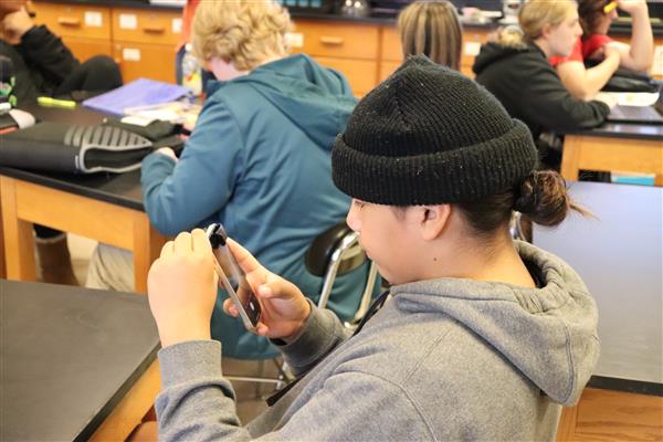 Student adding microscope to phone