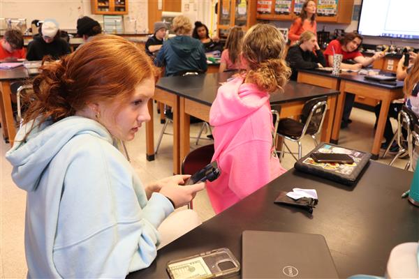 Student adding microscope to phone