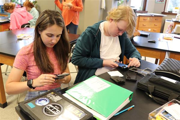 Students adding microscope to phone