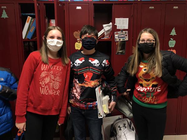 Three students in holiday sweaters