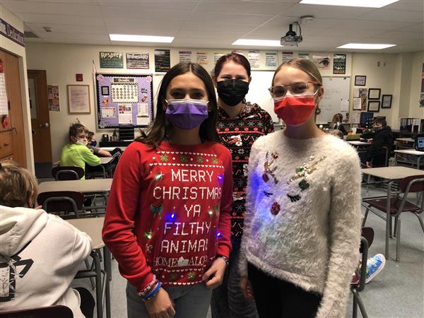 Three students in holiday sweaters